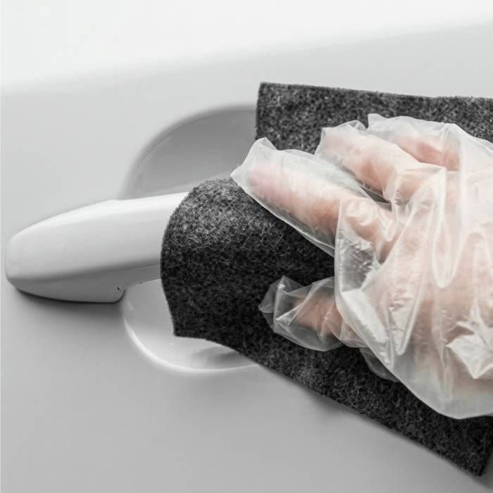 Gloved hand rubbing a grey NanoPolix cloth around a car door handle